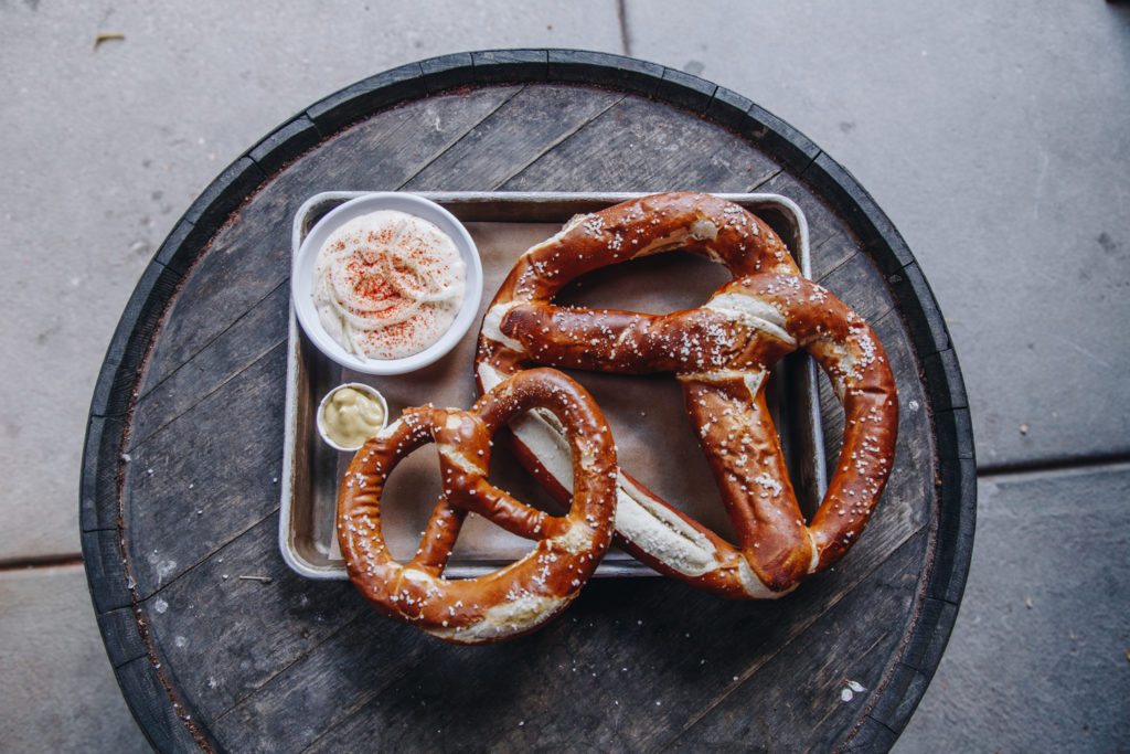 One jumbo soft pretzel and one large soft pretzel with dip on a tray.